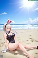 A woman in a bunny suit sitting on the beach.