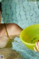 A woman in a swimming pool holding a yellow bowl.