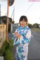 A woman in a kimono standing on the side of a road.