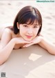 A woman laying on a sandy beach with her hand on her chin.