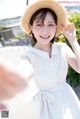 A woman wearing a straw hat taking a selfie.