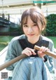 A young woman sitting on a boat holding a wooden stick.