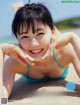 A woman in a blue bikini laying on the beach.