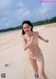 A woman in a pink bikini running on a beach.