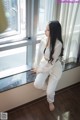 A woman sitting on a window sill looking out a window.