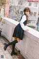 A young woman in a school uniform leaning against a wall.