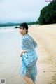 A woman in a blue dress standing on a beach.