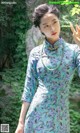 A woman in a blue and green cheongsam posing for a picture.