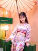 A woman in a kimono sitting on a bench holding an umbrella.