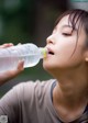 A woman drinking water from a plastic bottle.