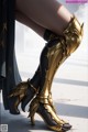 A close up of a woman's legs wearing a pair of gold boots.